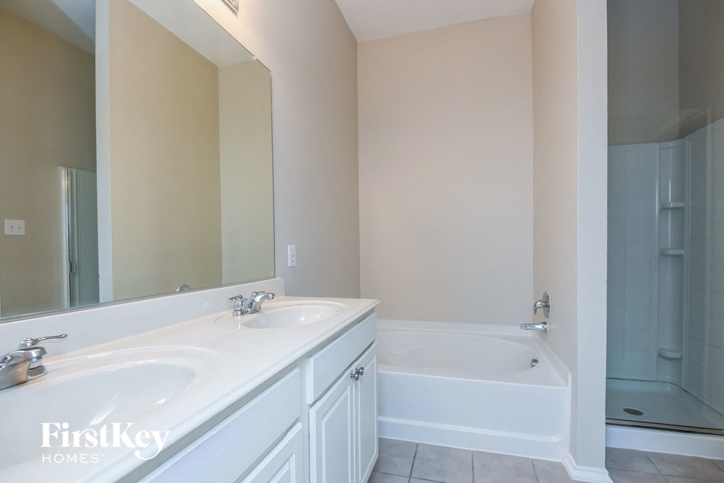 a bathroom with two sinks and a tub and a large mirror