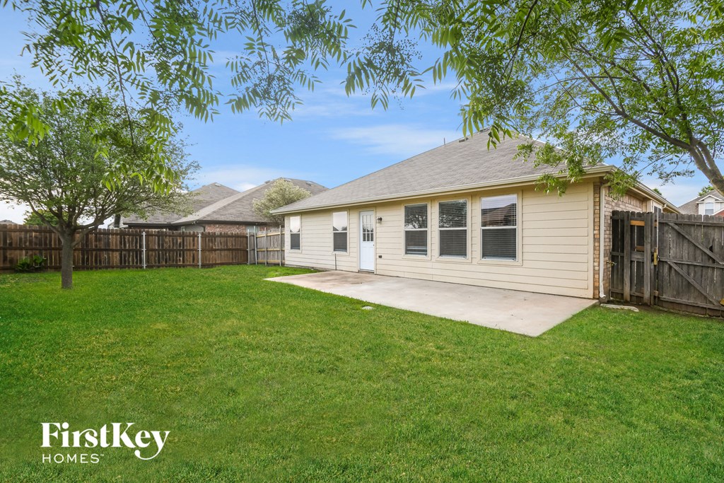 a backyard with a small white house and a yard with a wooden fence