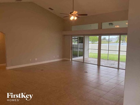 A spacious room with a ceiling fan and sliding glass doors leading to a grassy area.