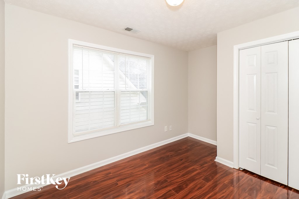 a bedroom with wood floors and a window and a white door