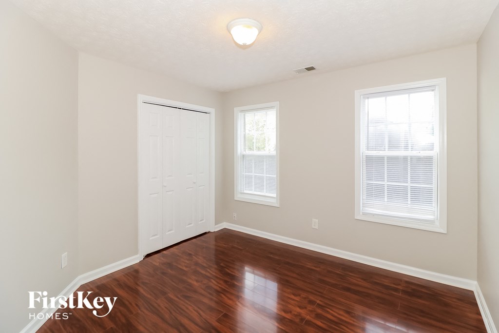 a bedroom with a hard wood floor and a white door and window