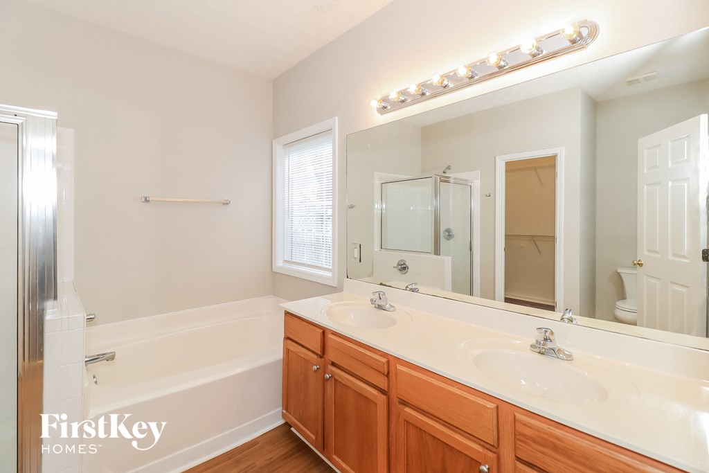 a bathroom with two sinks and a tub and a large mirror