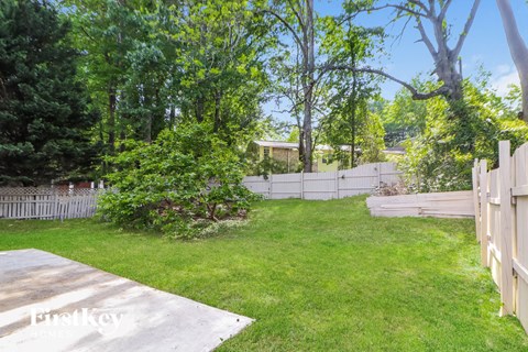 a backyard with a fence and grass and trees