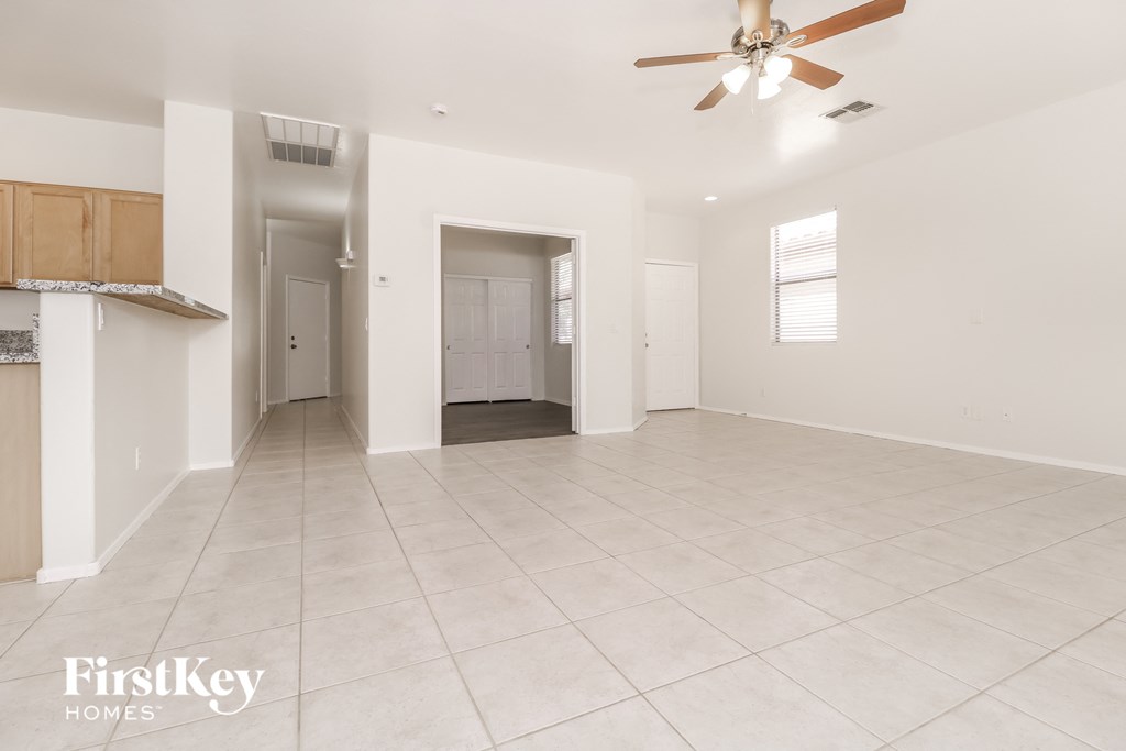 an empty living room and kitchen with a ceiling fan