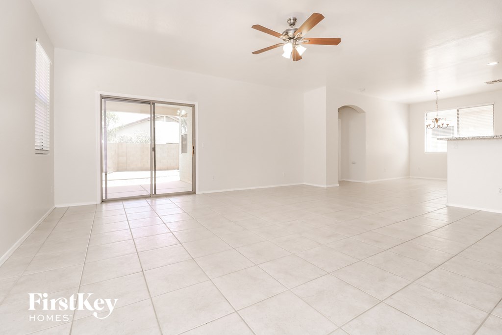 an empty living room with a ceiling fan and a door to a patio