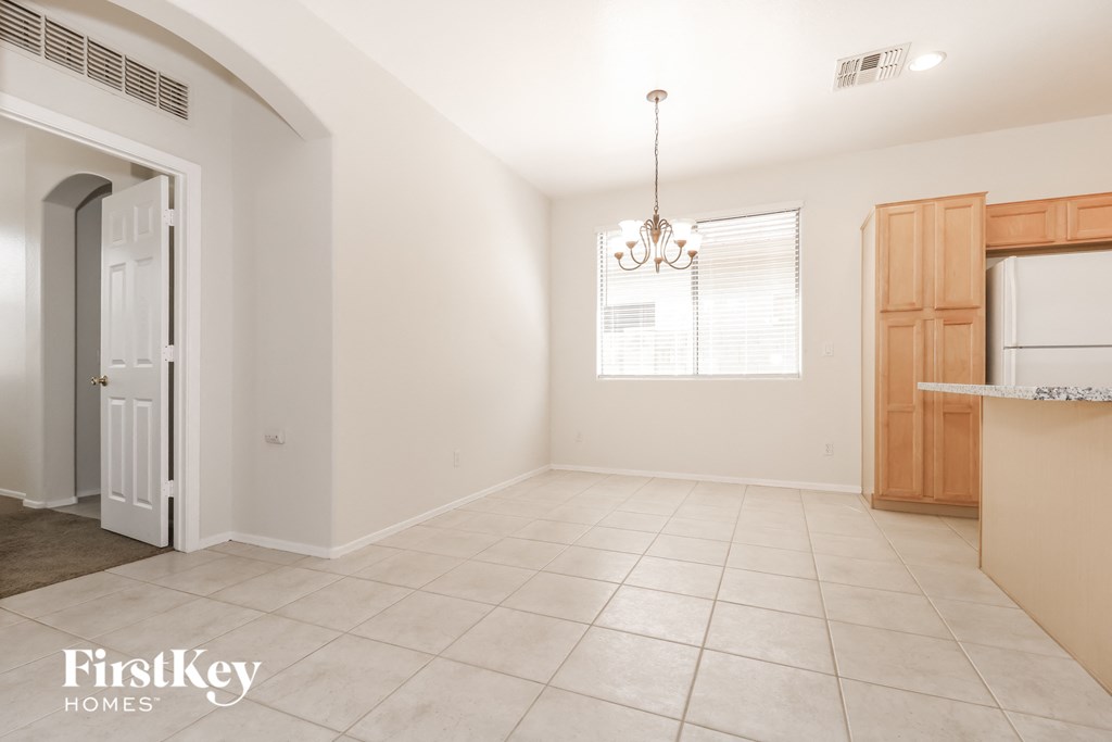 an empty kitchen and dining room with white tile floors and wood cabinets
