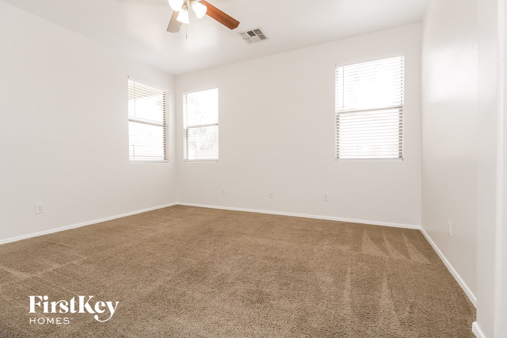 the spacious living room with carpeting and two windows