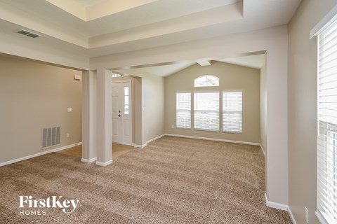 A spacious room with a carpeted floor and a doorway leading to another room.