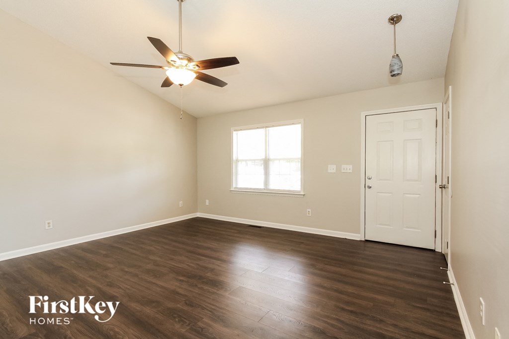an empty living room with a ceiling fan and a white door