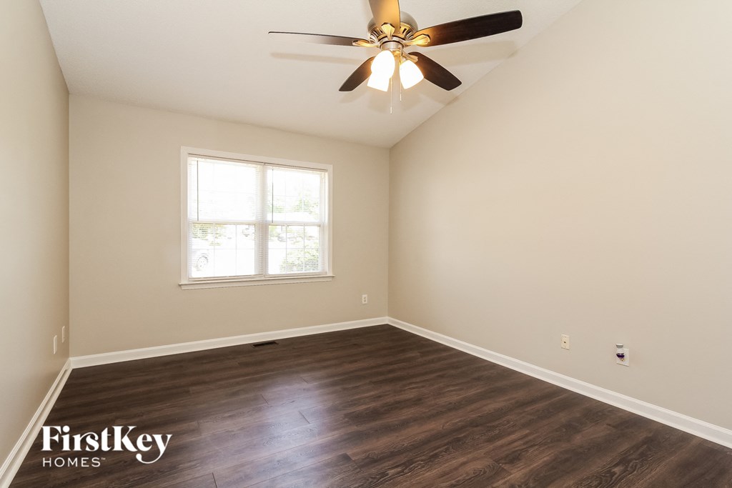the spacious living room with wood flooring and a ceiling fan