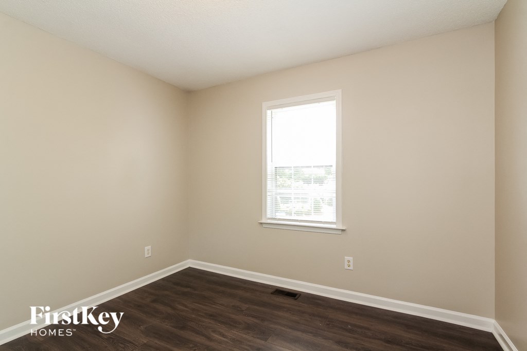 a bedroom with wood flooring and a window