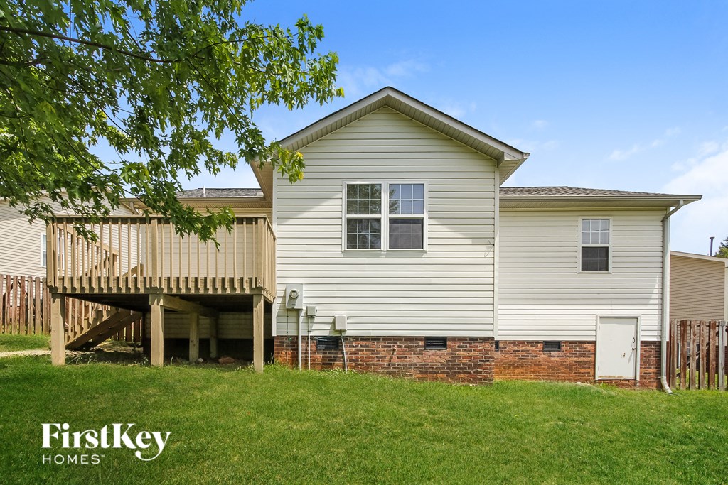 a white house with a deck and a brick retaining wall