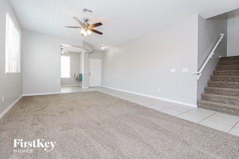 a carpeted living room with stairs and a ceiling fan