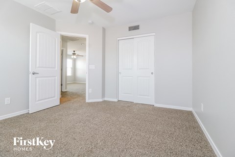 a bedroom with two closets and a carpeted floor and a ceiling fan