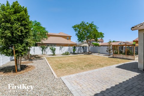 a backyard with a grass lawn and a white fence
