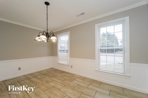 an empty dining room with two windows and a tiled floor