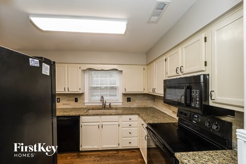 a kitchen with white cabinets and granite counter tops and black appliances
