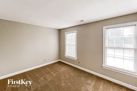 a bedroom with carpet and two windows