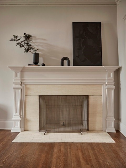 A fireplace with a plant on top and a picture behind it.