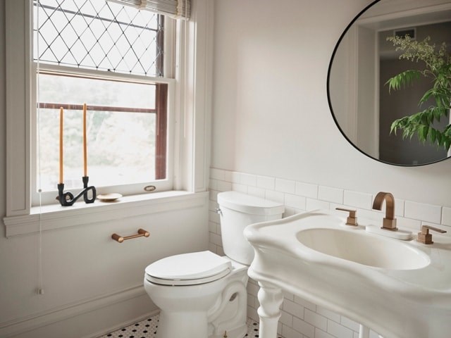 A white toilet and sink in a bathroom with a window.