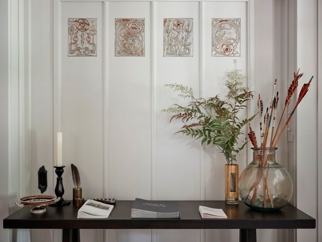 A table with a candle, a vase, and some books on it.