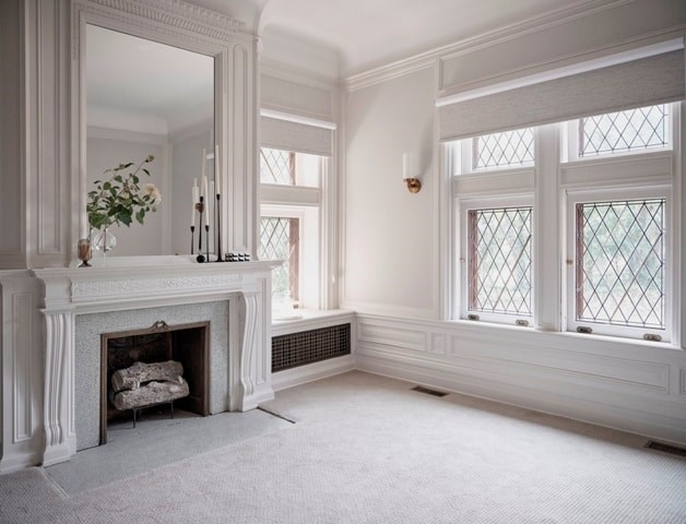 A white room with a fireplace and a mirror.