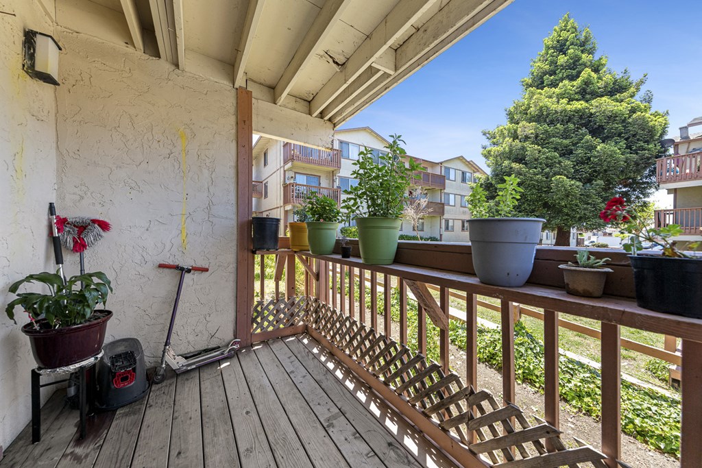 a balcony with a wooden railing and potted plants on it