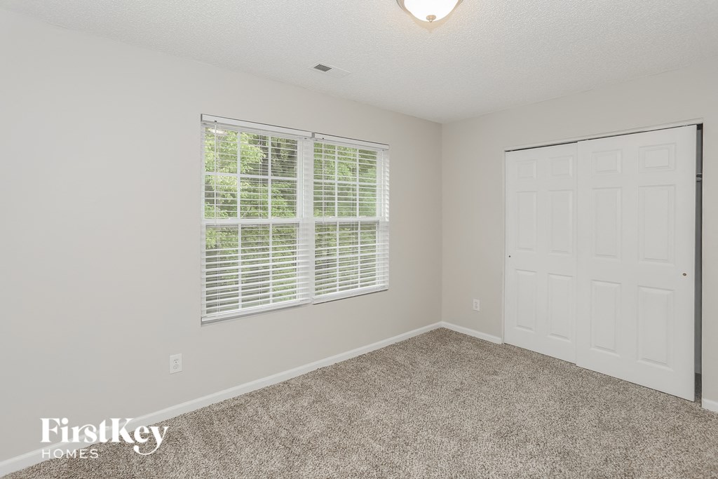 a bedroom with carpet and a white door and window