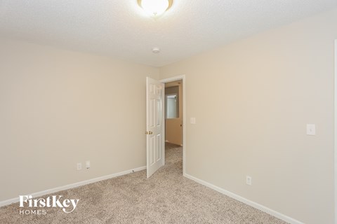 a spacious living room with carpet and a door to a hallway