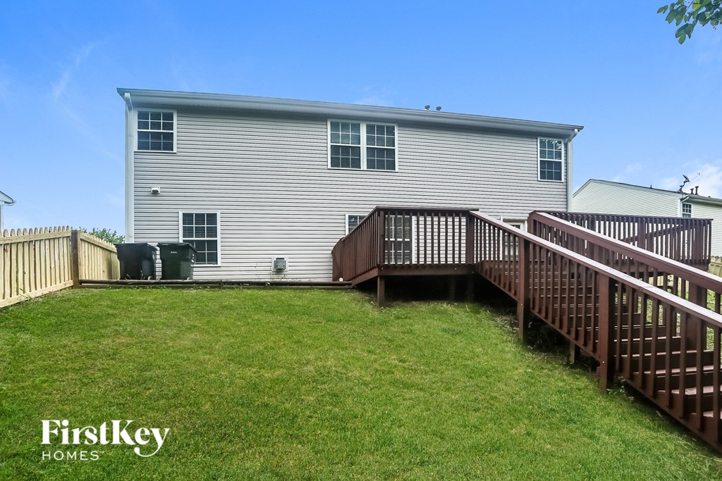 a backyard with a deck and a white house