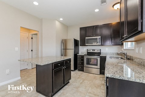 A kitchen with black cabinets and a granite countertop.