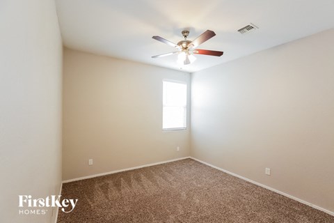 a bedroom with a ceiling fan and a carpet
