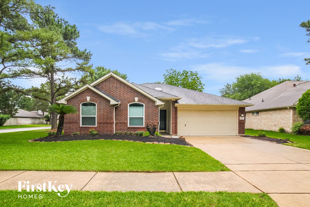 front view of a brick house with a driveway and grass