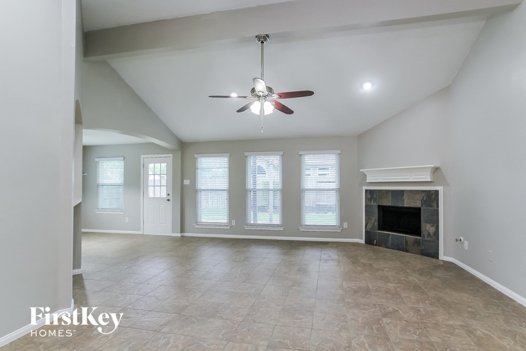 an empty living room with a fireplace and a ceiling fan