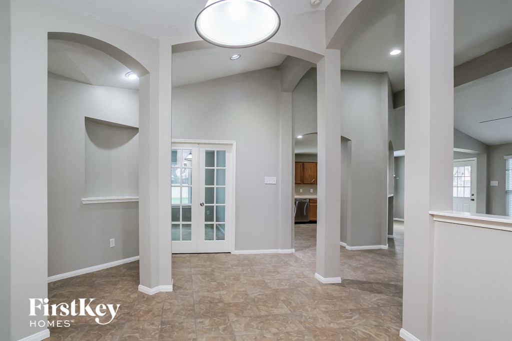 an empty living room with pillars and a ceiling light
