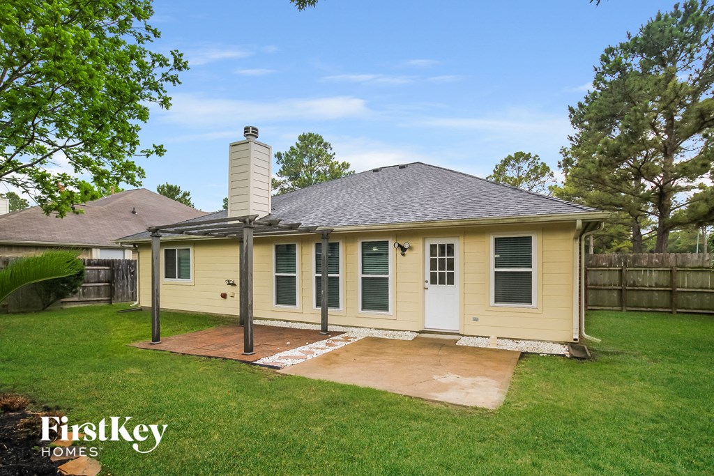a small yellow house with a patio in the yard