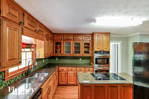 A kitchen with wooden cabinets and a granite countertop.