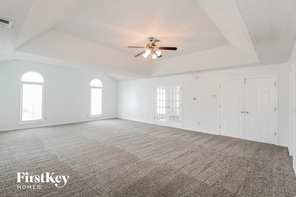 an empty living room with white walls and a ceiling fan