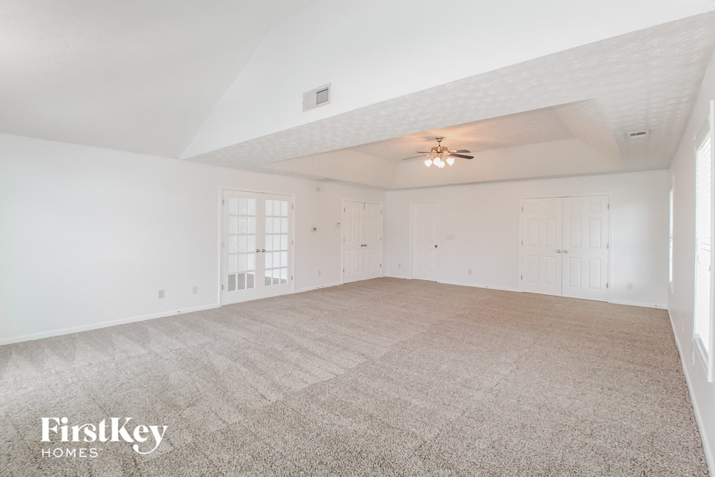 the living room of an empty home with white walls and carpet