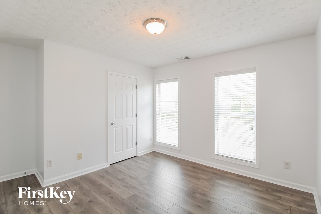 a living room with white walls and wood floors and a white door