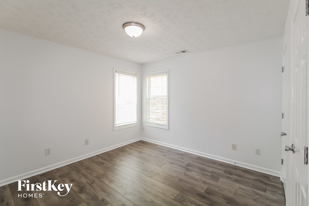 the living room of a home with white walls and wood floors