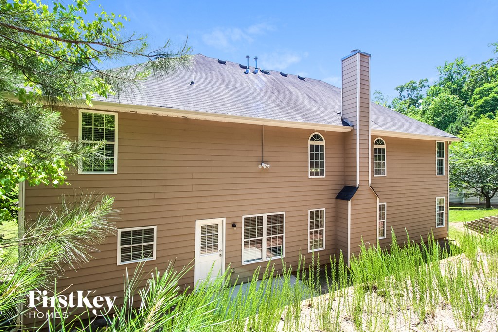 a brown house with a gray roof and tall grass