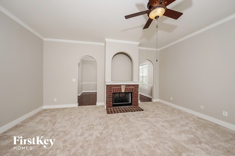 a living room with a fireplace and a ceiling fan