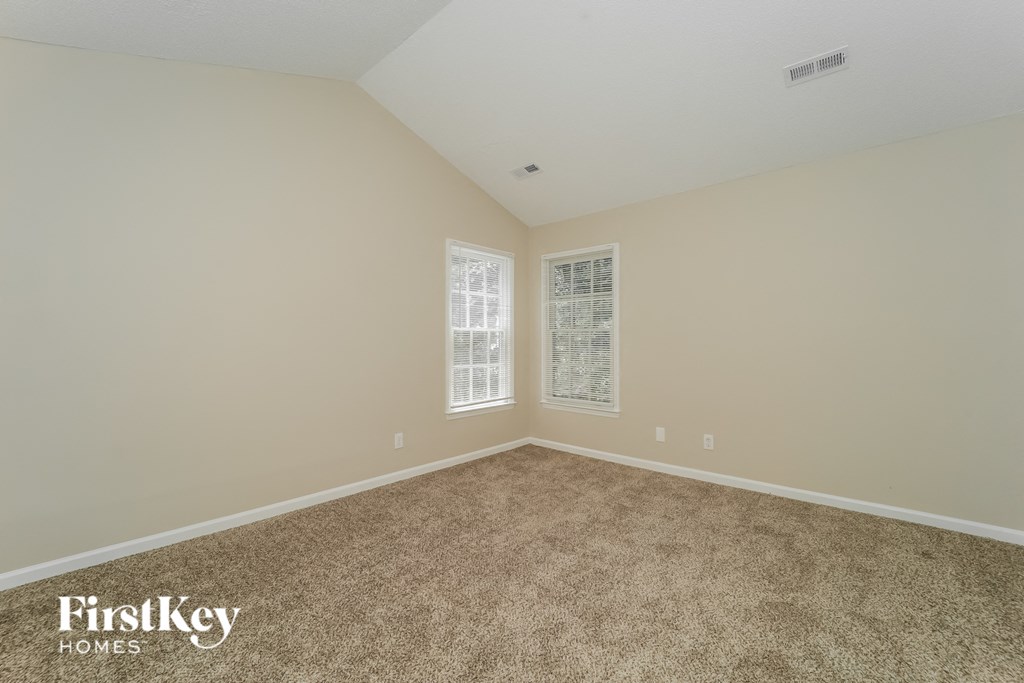 a empty room with carpet and two windows