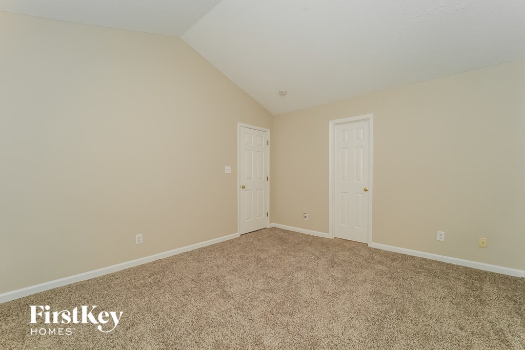 a bedroom with carpet and two doors
