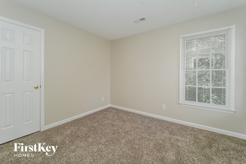 a bedroom with carpet and a window and a white door
