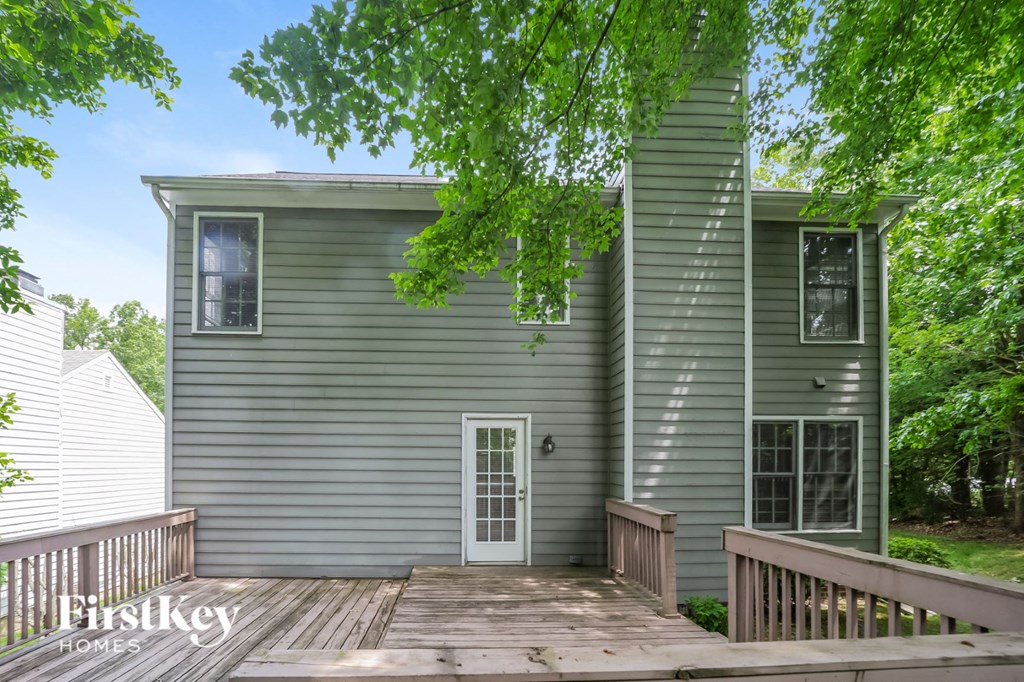a view of the back of a gray house with a wooden deck
