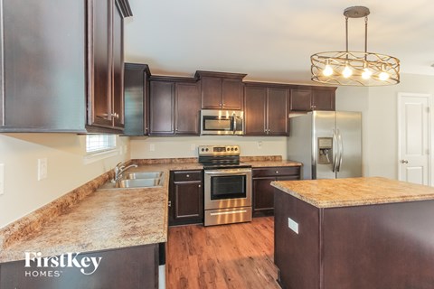 A kitchen with dark brown cabinets and a granite countertop.