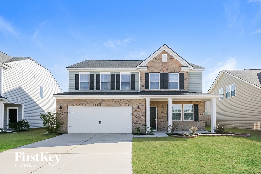 a home with a white garage door in front of a brick house