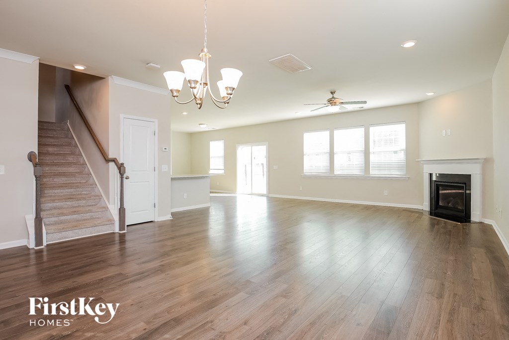 an empty living room with a fireplace and wood flooring